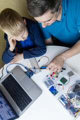 Programming for children. A teacher teaches a child at a robotics and IT school. Boy learning to code control board
