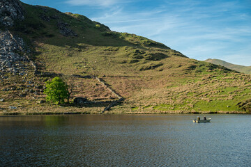 Anglers fishing from a boat on Llyn Dywarchen in the Eryri National Park, Wales.