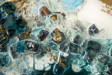 Closeup of epoxy resin with natural minerals, crystals and stones, painting of geode mixing vibrant pigments and colors. Texture of epoxy resin effect. Modern abstract liquid fluid art. 