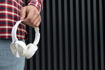 Stylish white headphones in hand close-up