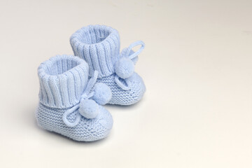 baby booties, for newborns, the first shoes with delicate feet on a light background