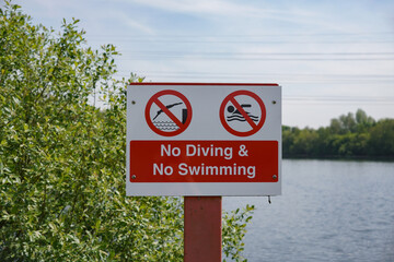 No diving and no swimming sign at side of lake. public safety notice beside deep water. 