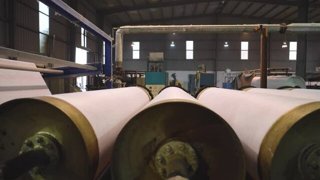 Rows Of Large Spinning Rollers With White Textile Fabric Inside Factory. Dolly Right Shot