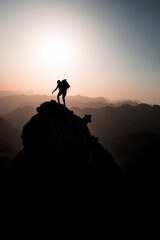 Fototapeta premium Silhouette of 2 mountaineers climbing and reaching a sharp pinnacle in the French Pyrenees