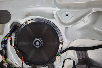 An automotive speaker is installed in a car door for audio equipment