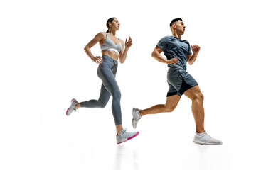 Two athletes sprinting, captured in moment of peak effort against white studio background. Synchronized movement. Concept of people in sport, healthy lifestyle, teamwork, motivation. Ad