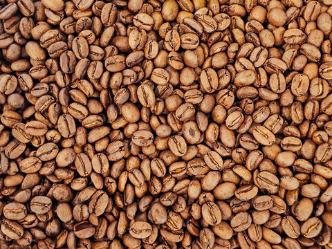 Real brown whole bean coffee texture pattern background come form organic farm and already roast for cafe coffee shop use