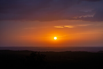 Orange and leaden sunset in the plains of La Mancha with the sun on the horizon and some clouds.