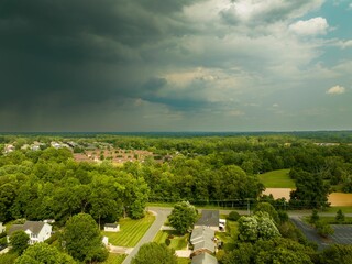 View of a suburban neighborhood surrounded with lush vegetation with a dark cloudy sky