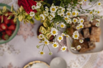 Closeup shot of chamomiles on a table with snacks. © Wirestock