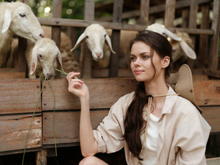 A woman is sitting in front of a wooden fence with sheep in front of her