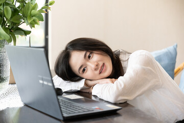 Asian woman sitting on chair at cozy office workplace and fallen asleep while she works on a...