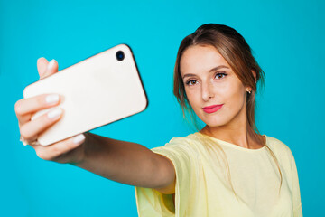 Cheerful coquettish millennial female in casual outfit and with beautiful makeup capturing selfie...