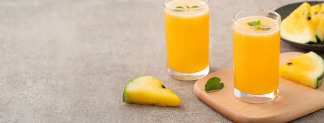 Fresh yellow watermelon juice in a glass cup on gray table background.