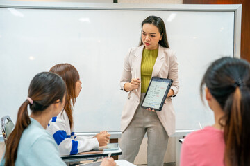 A woman is standing in front of a white board and holding a tablet