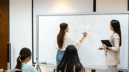 A group of people are in a classroom with a whiteboard