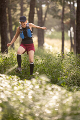 A woman is running through a forest with a backpack on