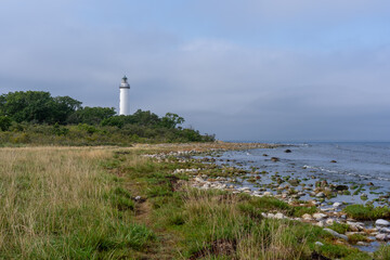 there is a lighthouse sitting high above the water near a grassy area