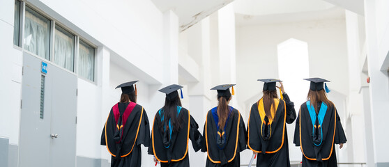 A group of women in graduation gowns are walking down a hallway