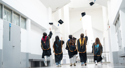 A group of graduates are running through a hallway, with their caps