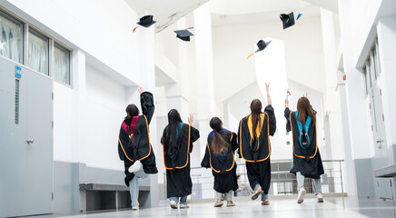 A group of graduates are running through a hallway with their caps