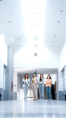 Four women are walking down a hallway in a building