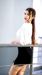 A woman in a black skirt and white shirt is standing on a railing