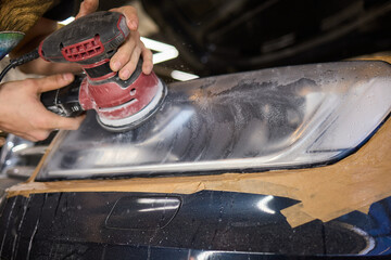 Person using a machine to polish automotive lighting on a car headlight