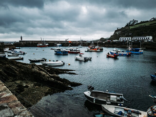 Fototapeta premium Numerous boats sail in the harbor under overcast skies, Mevagissey, UK