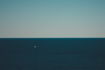 Mediterranean sea with a small boat and calm horizon with clear blue sky