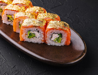 Luxury gold leaf sushi rolls on dark plate