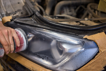 Person using a machine to polish automotive lighting on a car headlight