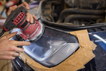 Person using a machine to polish automotive lighting on a car headlight