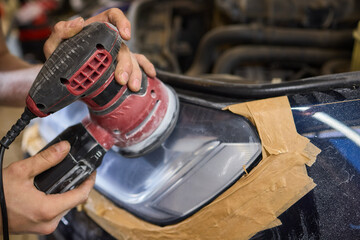 Person using a machine to polish automotive lighting on a car headlight