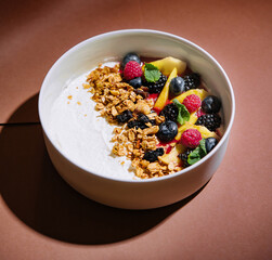 Fresh fruit yogurt bowl on elegant brown background