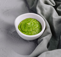 Fresh homemade green pesto sauce in white bowl
