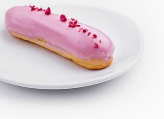 Pink iced eclair on white plate