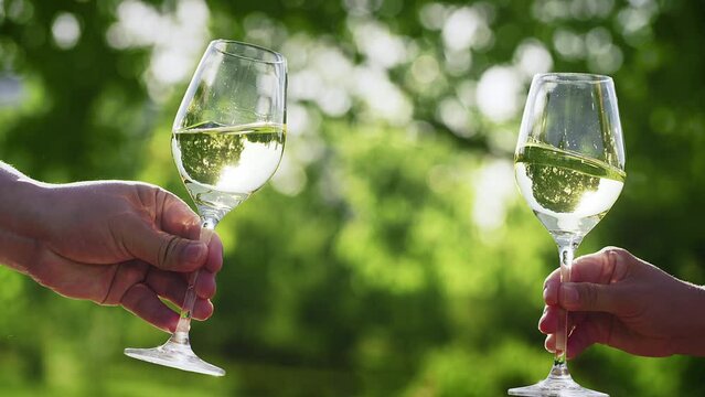 Couple with glasses of white wine outdoors, closeup