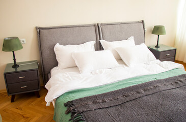 a large bed with pillows and blankets in a bedroom with two lamps