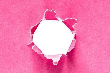 Torn holes in pink paper on a blank white background