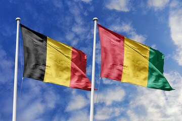 3d illustration. Belgium and Guinea Flag waving in sky. High detailed waving flag. 3D render. Waving in sky. Flags fluttered in the cloudy sky.