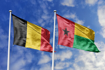 3d illustration. Belgium and  Guinea-Bissau Flag waving in sky. High detailed waving flag. 3D render. Waving in sky. Flags fluttered in the cloudy sky.