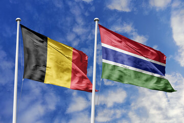 3d illustration. Belgium and Gambia Flag waving in sky. High detailed waving flag. 3D render. Waving in sky. Flags fluttered in the cloudy sky.