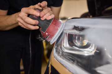 Person using a machine to polish automotive lighting on a car headlight