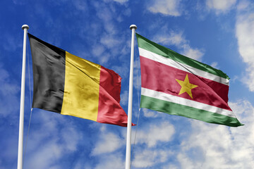 3d illustration. Belgium and Suriname Flag waving in sky. High detailed waving flag. 3D render. Waving in sky. Flags fluttered in the cloudy sky.