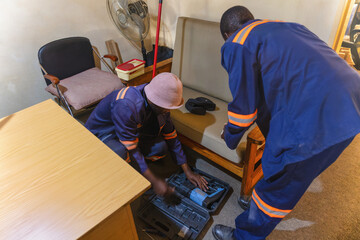 two african workers with a drill machine fixing internet in a room