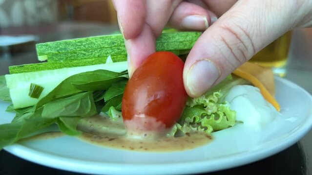 on a plate, cucumber, tomatoes and greens, dip Cherry tomato in Light sauce, diet food, vegetarianism, diversify your food