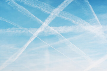 Airplane condensation trail with lines of clouds over blue sky background.