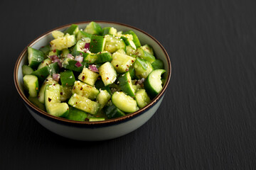 Homemade Smashed Cucumber Salad in a Bowl on a black background, side view. Copy space.