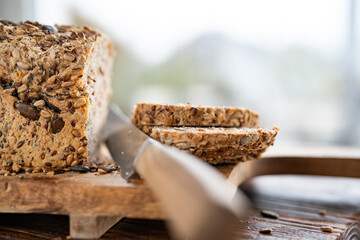 Freshly sliced multigrain bread on wooden cutting board with kniffe. Close-up with short depth of...